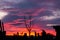 Red-blue sunset with dark clouds on the outskirts of the village. The outlines of an old broken fence against the backdrop of a