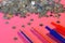 Red and blue transparent fountain pens lie next to silvery stars on a pink background. The system of performance and grades in