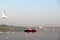 red boat rowing into the middel of a river early in the morning in the middle of seagulls