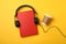 Red book, headphones and coffee cup on yellow background