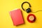 Red books, headphones and cup of coffee on yellow background