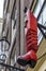 A red boot hangs on the wall of a house in Amsterdam. History and ancient traditions. Close-up. Vertical