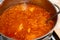 Red borsch with cabbage and fat rich meat in a pan, close-up from above