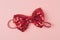Red bow tie with spangles on light pink background