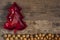 Red bowl in christmas tree shape on ground of walnuts, rustic wooden floor background