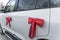 Red bows tied to the door handles of a white car. Wedding car decoration