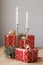 a red box with a gift and a gold ribbon. festive decor of Christmas trees and candles on the table is small. preparing