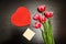 Red box in heart shape, clean card, pink tulips. Black table. top view, space for text