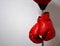 Red boxing gloves hanging on punching ball pole on concrete wall