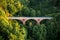 Red brick arch bridge over a lush green forest