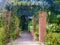 A red brick arch full of climbing plants in the park.