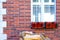 Red brick building. White balcony. Flowerpots White Windows