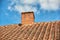 Red brick chimney designed on the roof of residential house or building outside against a cloudy sky background with