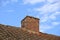 Red brick chimney designed on slate roof of a house building outside with blue sky background and copyspace. Exterior