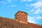 Red brick chimney designed on slate roof of a house building outside with cloudy blue sky background and copyspace