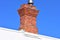 Red brick chimney on white roof