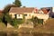 Red brick dilapidated abandoned partially overgrown large family house built on stone foundation on edge of river bank surrounded