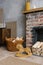 Red brick fireplace with firewood and a basket of firewood near it, children`s wooden toy horse gurney in the living room in the