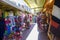 A red brick footpath lined with colorful hats, dresses, purses, jackets and blankets with people walking at Olvera Street