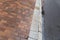 Red brick and gray granite sidewalk alongside an asphalt street all wet with rain