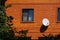 Red brick house with decorative window grates and white satellite dish