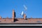 Red brick roof with chimneys and tv antennas on a clear blue sky