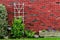 Red brick wall at back yard with green plants at home building decorated with tree, rocks, bushes and flower pot.