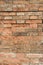 Red brick wall in the cracks. Shattered wall close up. Old grunge ruined wall texture background