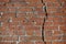 Red brick wall is divided by a vertical crack. Separation concept