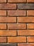 A red brick wall, rectangular shaped bricks with a rough texture.