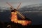 A red brick windmill illuminated at night