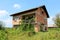 Red bricks abandoned family house with broken windows and front wire fence overgrown with high uncut grass and crawler plants