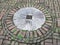 Red bricks and white cement in circle on ground with weeds