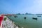 Red bridge and coastal fishing boats moor at pier on sea shore with clear water over blue sky