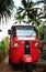 Red bright tuk tuk on a background of palm trees. Southeast Asia travel, traditional transport Sri Lanka