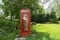 Red British phone booth with an idea to share books in public place. Relaxing park