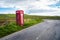 Red British telephone booth on a country road