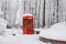 Red British telephone booth used as street library in winter translated from Russian