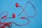 Red broken torn headphones on classic blue background. Close up broken old earphone