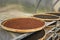 Red or brown peppercorns drying in drying room or box on plates of reed on black pepper plantation. Drying of red