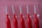 Red brushes for braces, toothbrushes for interdental spaces on pink background in plastic box, closeup. Macro. The concept of good