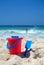 Red bucket and blue spade on sunny sandy beach