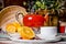 red buckthorn tea in a kettle and a cup of oranges.