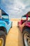 A red buggy and a blue buggy standing over orange dunes.