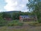 Red building of AbiskoJaure STF mountain hut. Green hills, birch forest on the Kungsleden Trail, summer blue sky