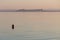 A red buoy on Trasimeno lake at sunset, with Castiglione del Lag