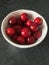 Red, burgundy sweet ripe cherries in a white plate on a black table background