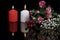 Red burning candles, red and white flowers, greeting card on black background. Reflection in dark glass mirror. Love and passion