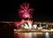 Red bursts of fireworks streaming up from the Sydney Opera House at night