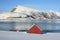 Red cabin on icy fjord